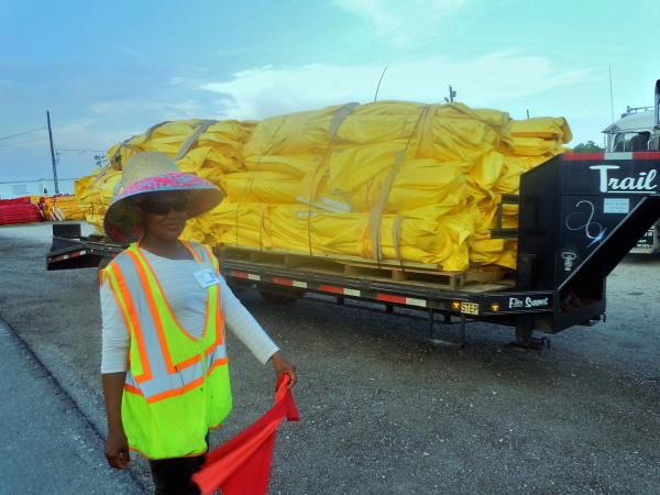 Etanisla Hernandez is a flag girl on the Hopedale cleanup site; she guides trucks and forklifts unloading protective barriers - Photo: Annie Correal