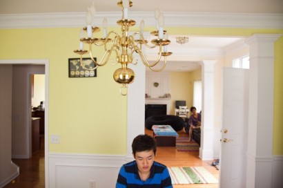 Alex Yoo sits in his Paramus, N.J. home while his guardian looks on from the living room. (Photo by Peter Moskowitz)
