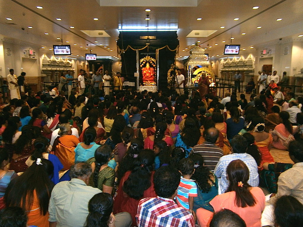 Devotees in the Maha Mantapa, the main prayer hall of a Hindu temple in Queens.